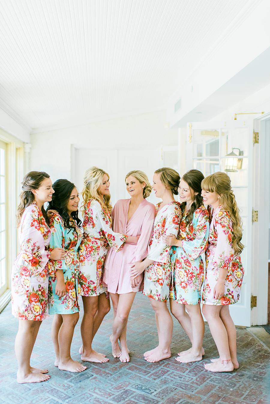 Bridesmaids laughing in floral robes at the Ribault Club